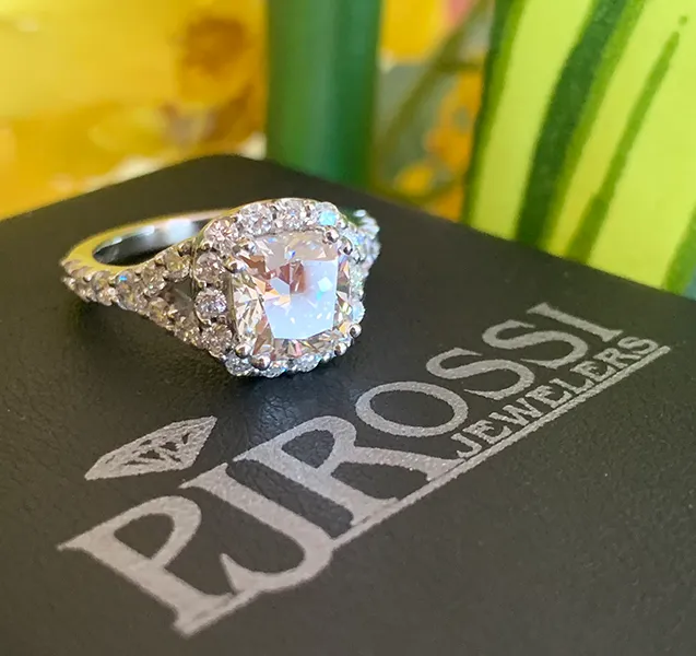 Stunning engagement ring with a large center stone and intricate detailing, displayed on P.J. Rossi Jewelers' logo.