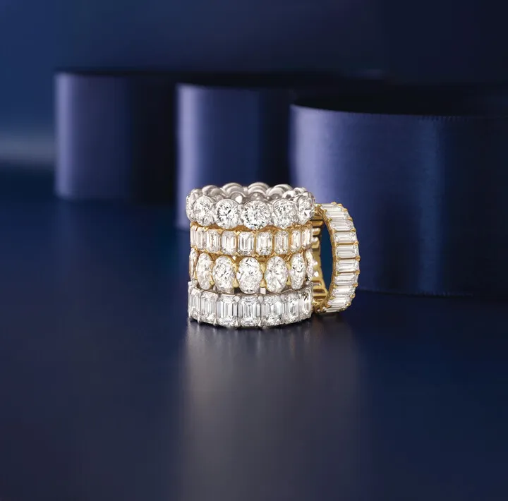 Elegant silver women's wedding band with sparkling diamonds, reflecting on a marble surface. Shop now at Premier Diamond Center.