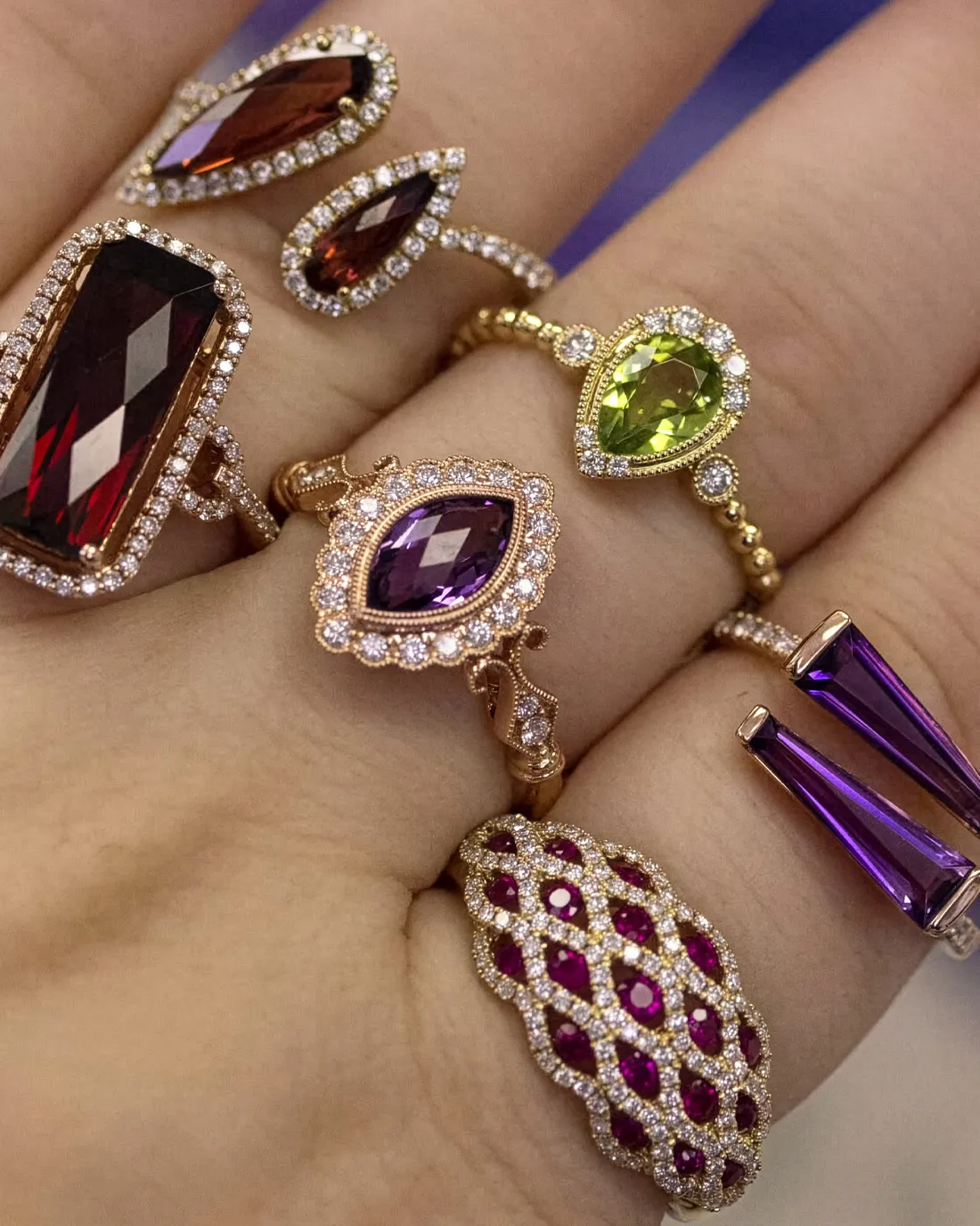 Colorful gemstone rings featuring purple, green, and red stones.