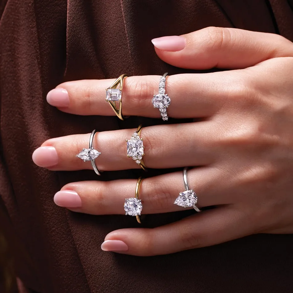 A hand displaying multiple elegant engagement rings in various styles and metals. Visit Premier Diamond Center for custom design