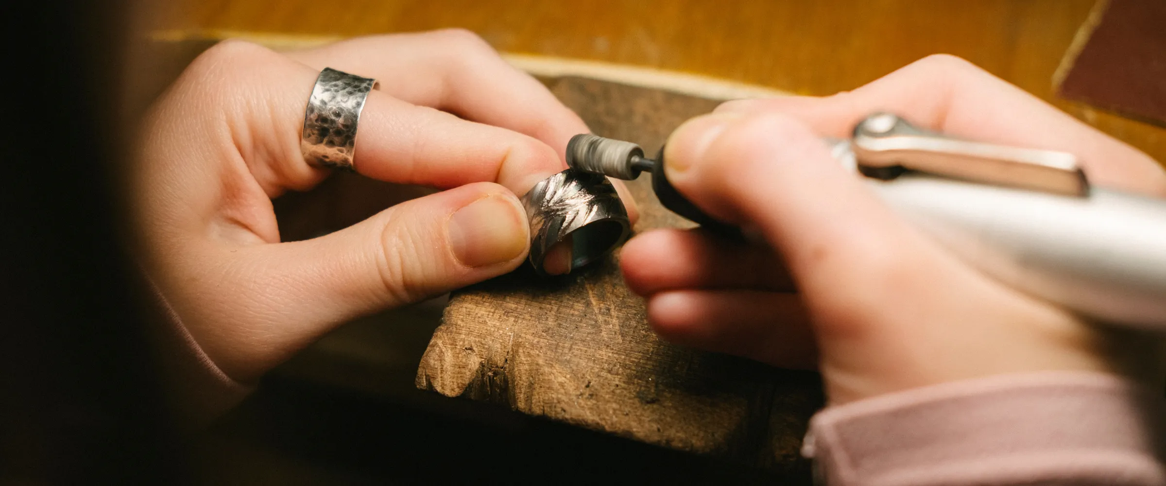 Jeweler refining a silver ring with a tool, showcasing craftsmanship at Premier Diamond Center.