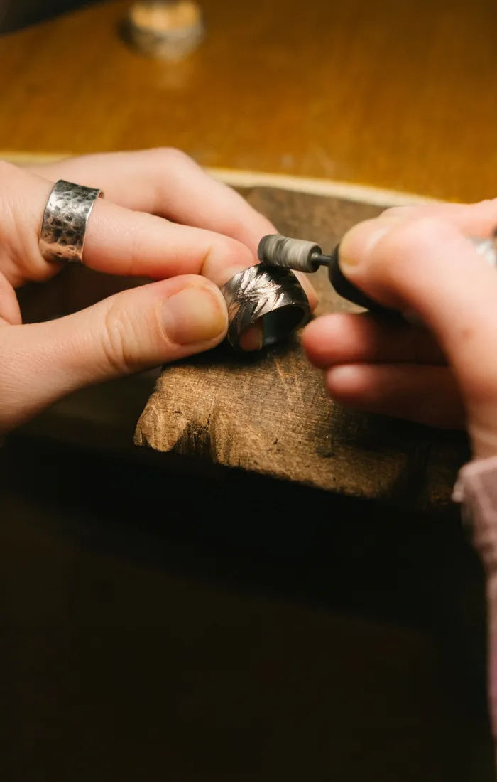 Jeweler refining a silver ring with a tool, showcasing craftsmanship at Premier Diamond Center.