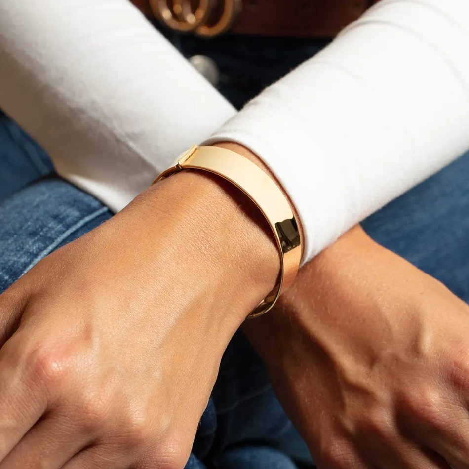 Close-up of a gold bracelet on a wrist, showcasing a sleek and modern design. Visit Premier Diamond Center for more.