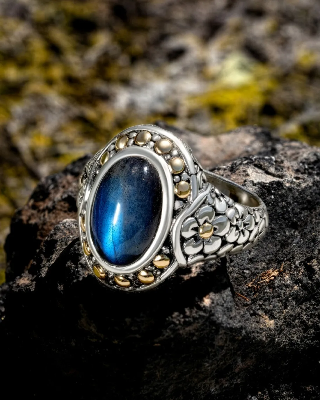 Elegant silver ring with a blue gemstone and gold detailing.
