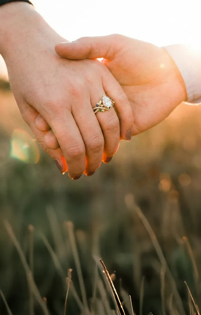 Two hands holding each other with an engagement ring, symbolizing love. Click to design engagement rings at Premier Diamond Cent