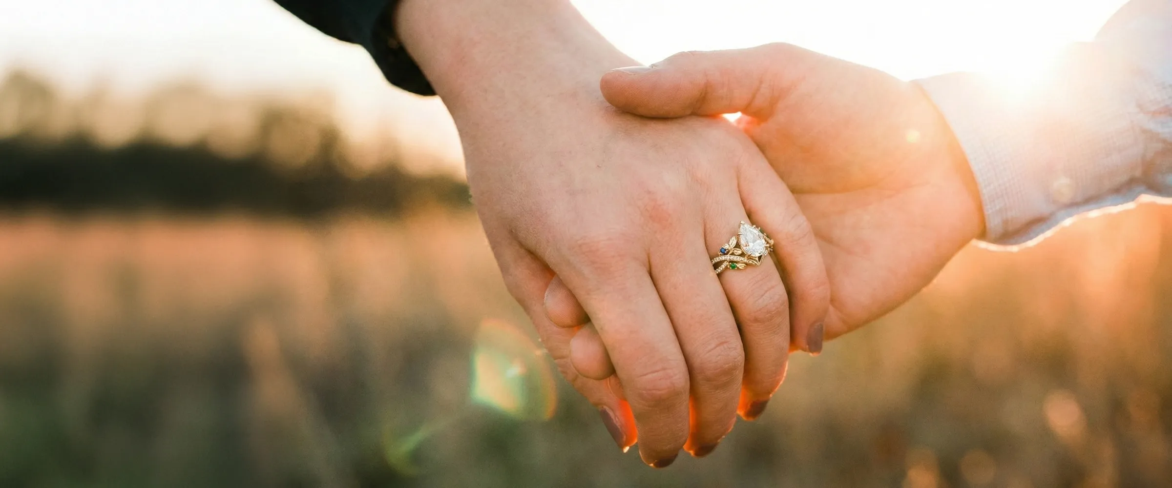 Two hands holding each other with an engagement ring, symbolizing love. Click to design engagement rings at Premier Diamond Cent