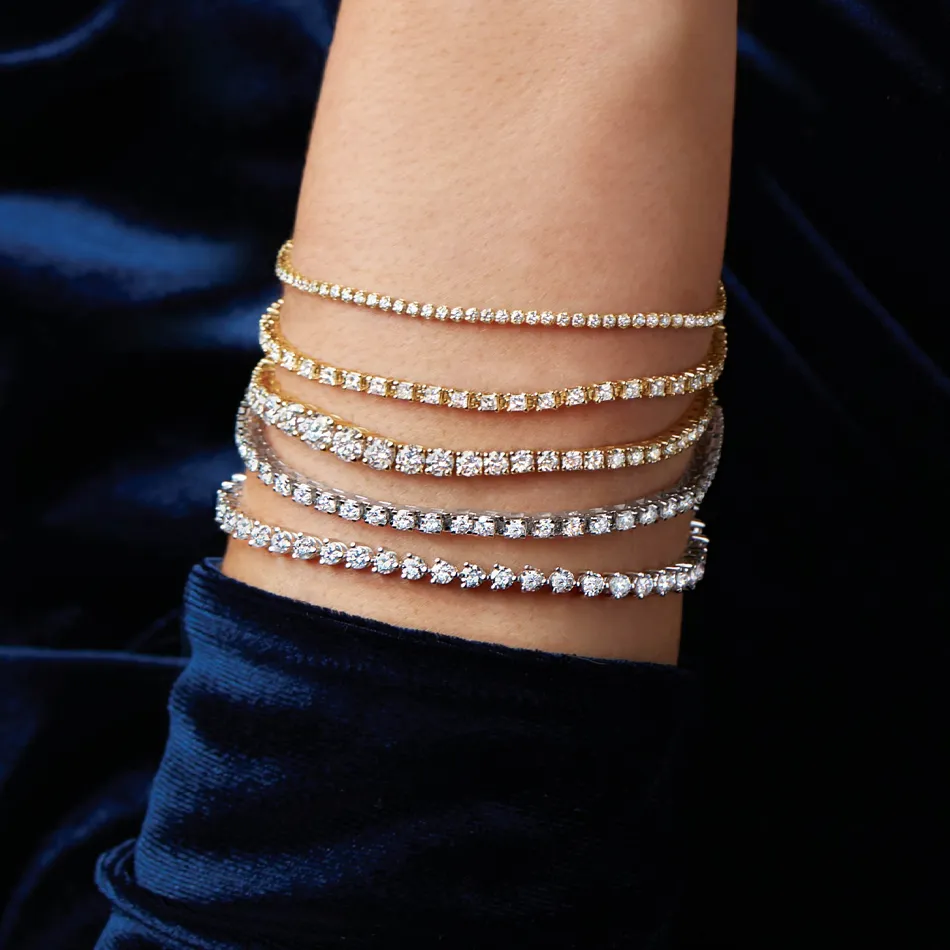 Elegant stack of diamond bracelets in gold and silver on a wrist, showcasing luxury jewelry from Premier Diamond Center.