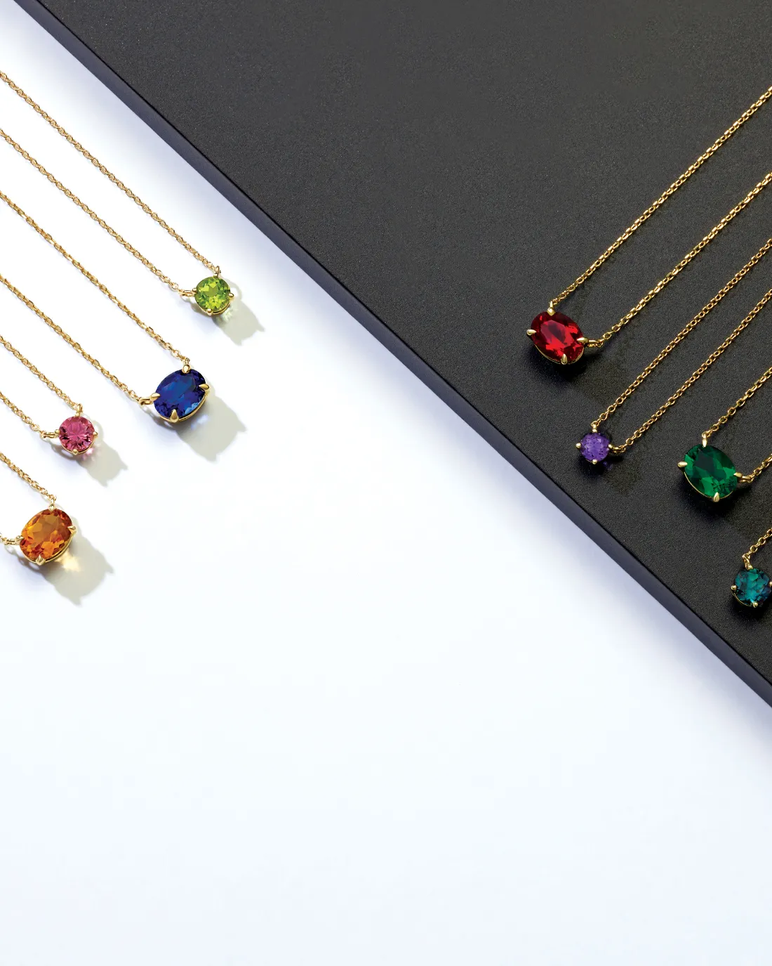 Colorful gemstone necklaces on gold chains displayed on a black and white background. Click to Shop Now at Premier Diamond Cente