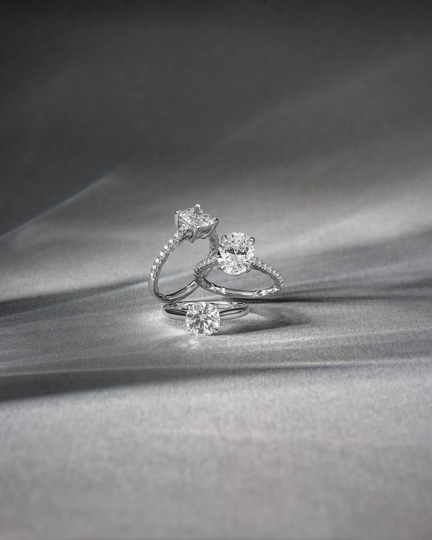 Three elegant diamond rings by A.Jaffe displayed on a soft gray background. Visit Quest Fine Jewelers in Fairfax for more.