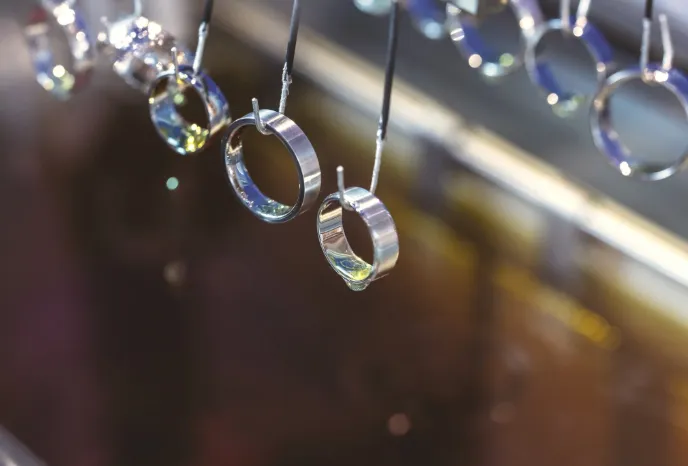 Shiny silver rings hanging on display at Quest Fine Jewelers in Fairfax, showcasing fine jewelry options.