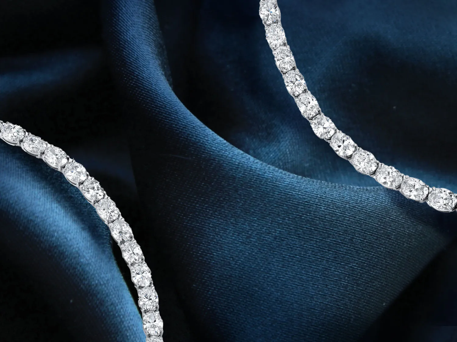Elegant gold and silver rings with diamonds on a soft fabric background. Click to make an appointment at Quest Fine Jewelers.