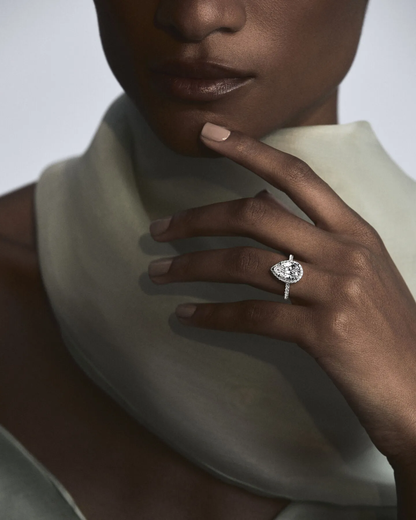 Close-up of a woman's hand showcasing a sparkling engagement ring by A.Jaffe, set against a soft, elegant background.