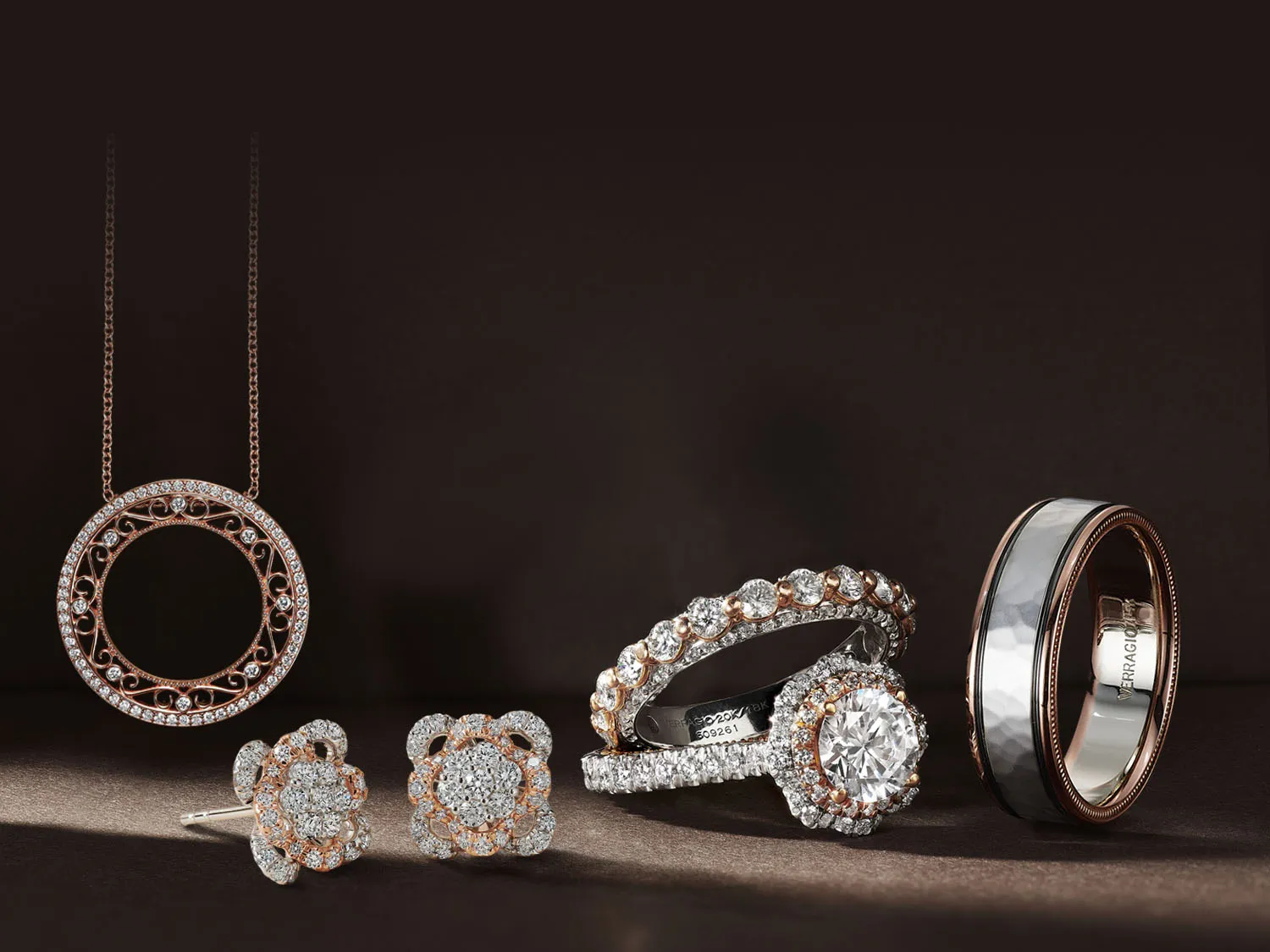 Elegant gold and silver rings with diamonds on a soft fabric background. Click to make an appointment at Quest Fine Jewelers.