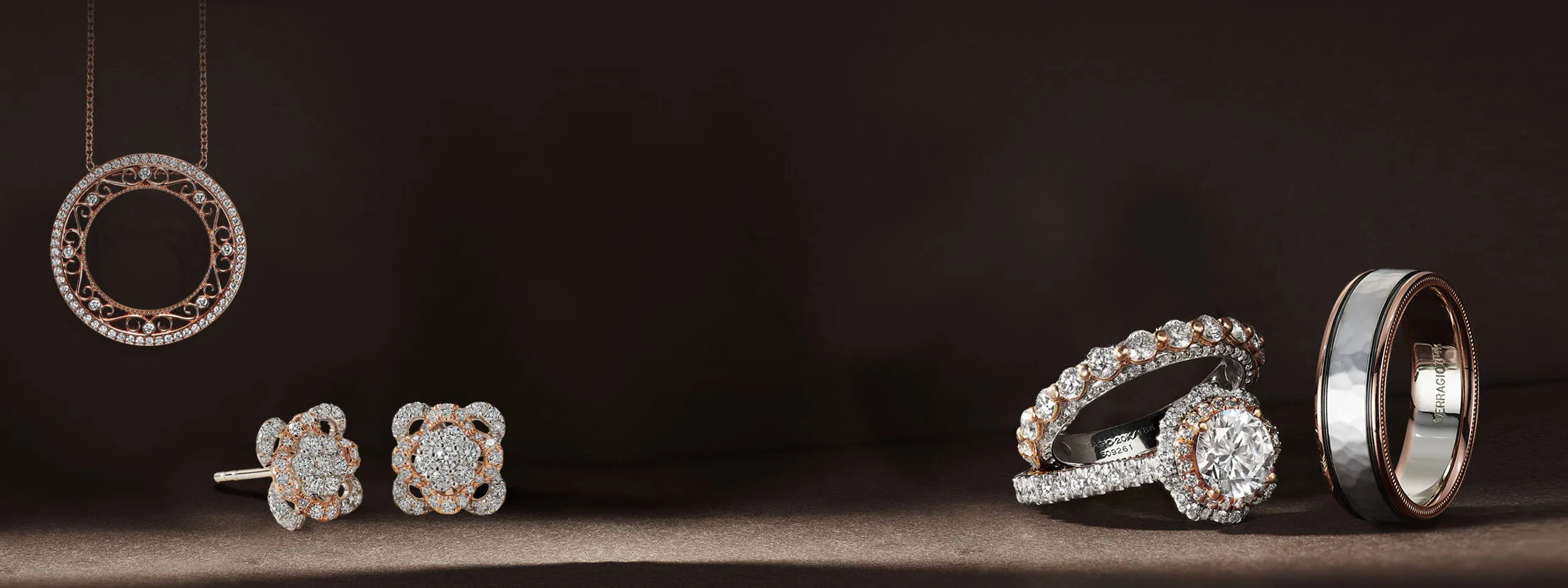 Elegant gold and silver rings with diamonds on a soft fabric background. Click to make an appointment at Quest Fine Jewelers.