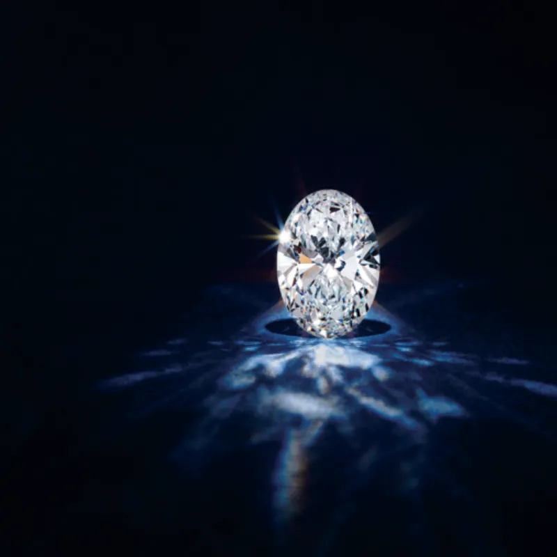 Sparkling oval lab-grown diamond on a dark background. Click to learn more about lab-grown diamonds.