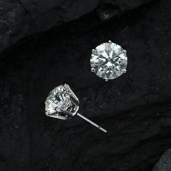 Diamond stud earrings on a dark background, showcasing their brilliance. Ideal for timeless gifts. Visit Quest Fine Jewelers.