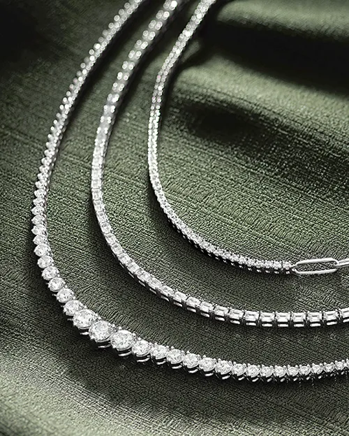 Diamond necklace laying on a dual tone surface | Diamond Necklaces available at Raleigh Diamond Fine Jewelry Raleigh, NC
