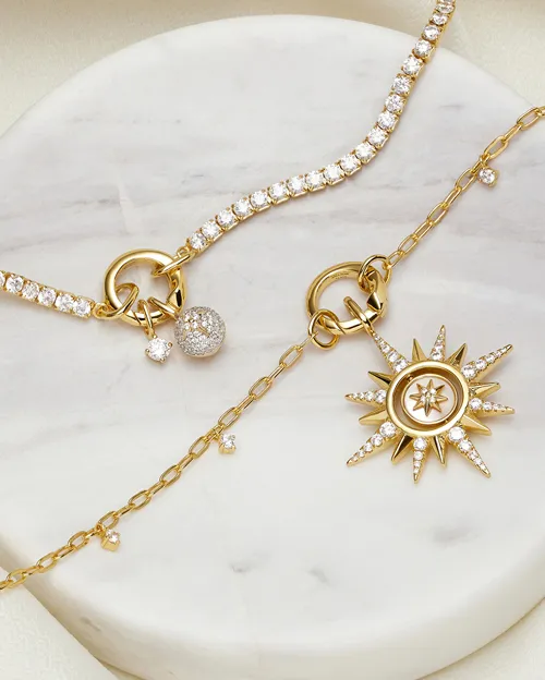 Bracelets with diamond charms on marble | Diamond Charms and Pendants available at Raleigh Diamond Fine Jewelry Raleigh, NC
