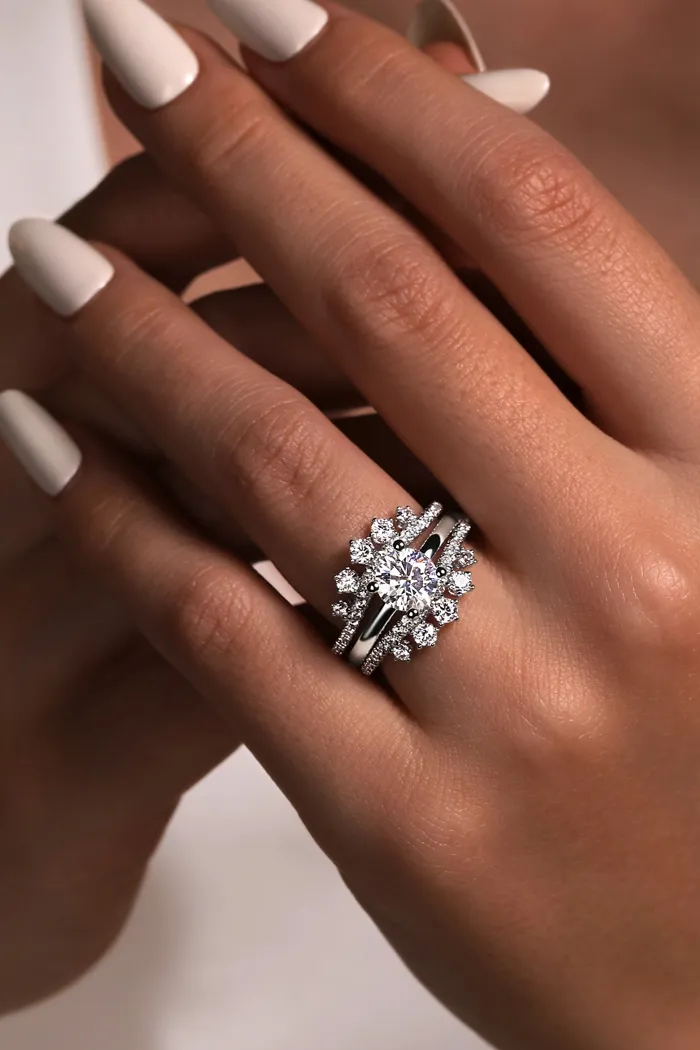 Elegant diamond engagement ring set on a hand with manicured nails, showcasing intricate design and sparkle.