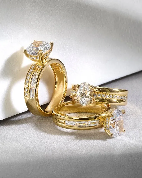 Three elegant gold rings with diamonds, showcasing a stunning engagement ring. Click to shop now at Reiniger Jewelers.