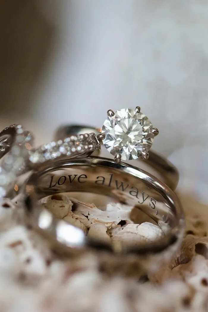 Close-up of engagement rings with a diamond and engraved message 