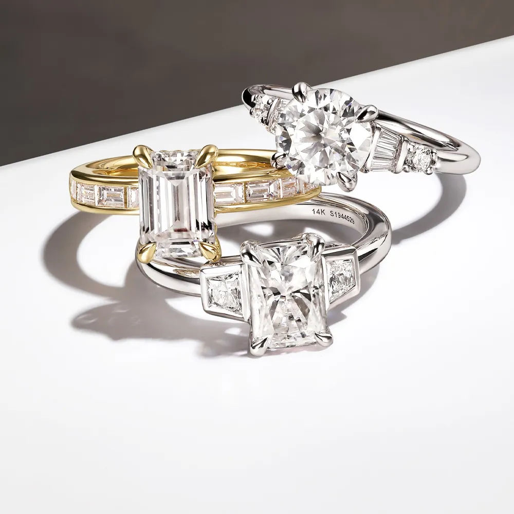 Three elegant diamond engagement rings featuring various cuts and settings, displayed on a white surface.