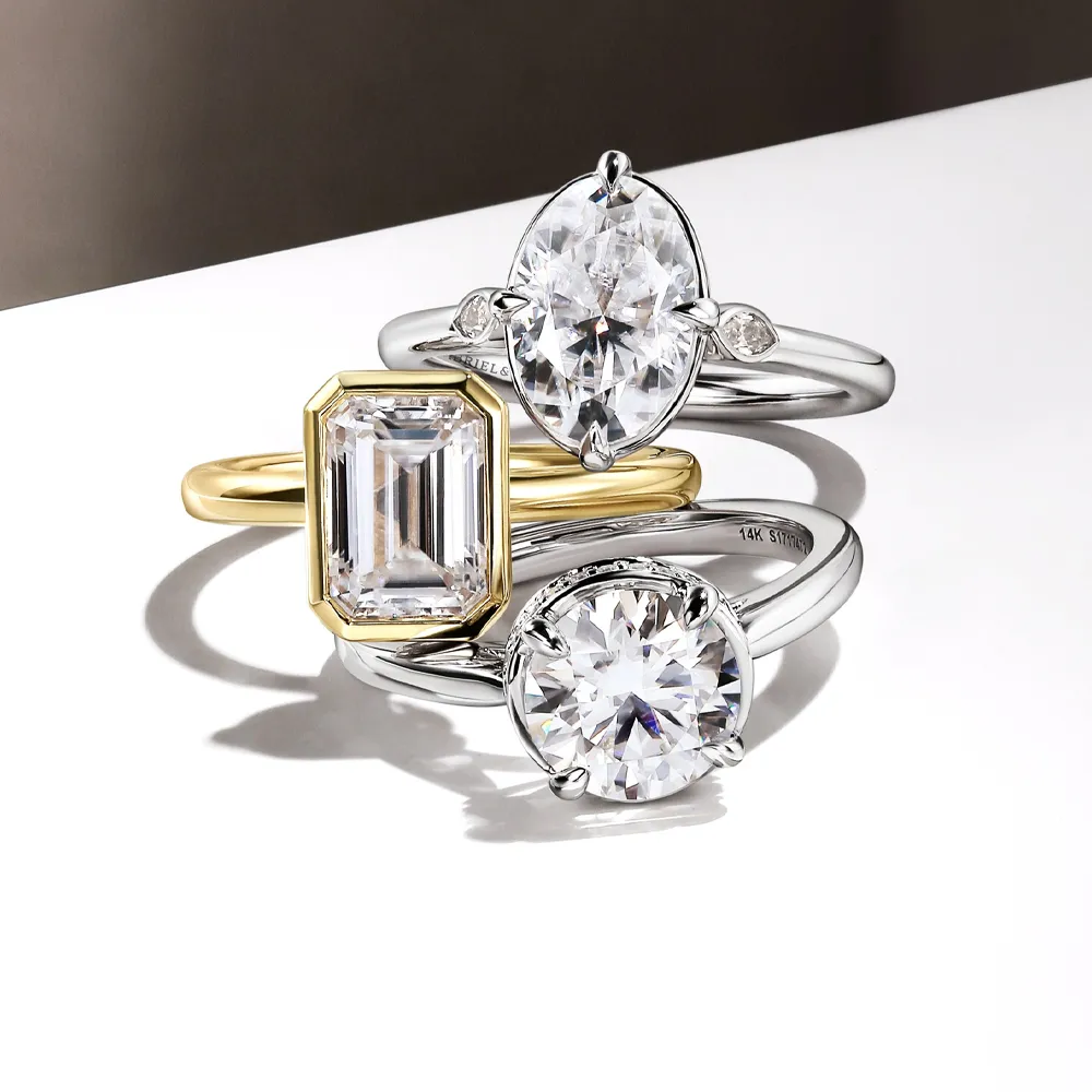Three elegant engagement rings featuring various diamond cuts and settings, displayed on a sleek surface. Explore now.