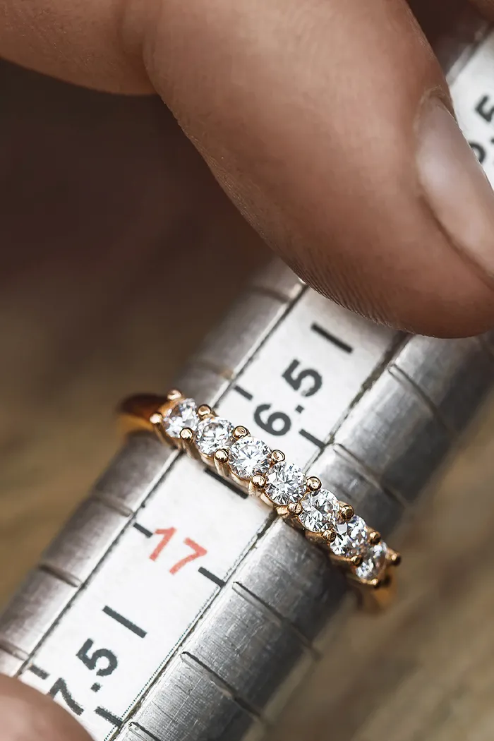 A hand holding a diamond ring on a ring sizer, measuring size 17. Visit Reiniger Jewelers for fine jewelry.