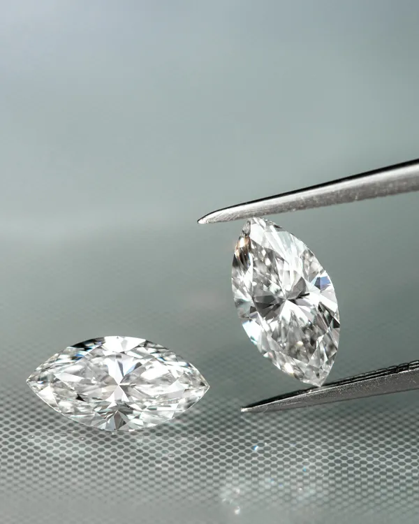 Two sparkling diamonds, one held by tweezers, showcasing their brilliance. Click to shop now at Reiniger Jewelers.