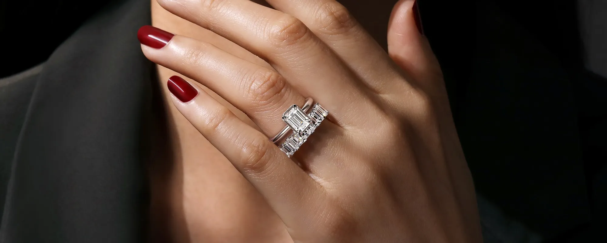 Elegant hand wearing a diamond engagement ring with a rectangular center stone and side stones, showcasing fine jewelry.