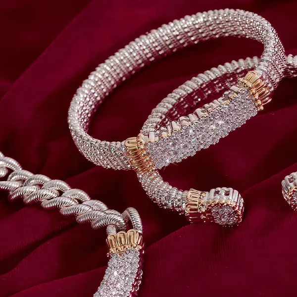 Silver and gold bracelets with diamond accents on a red fabric background.