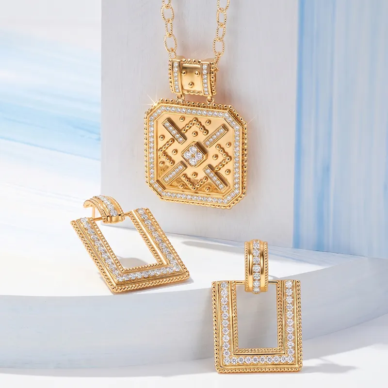 Gold and diamond pendant and earrings set displayed on a light background.