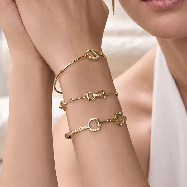 Gold bracelets with diamond accents on a woman's wrist.