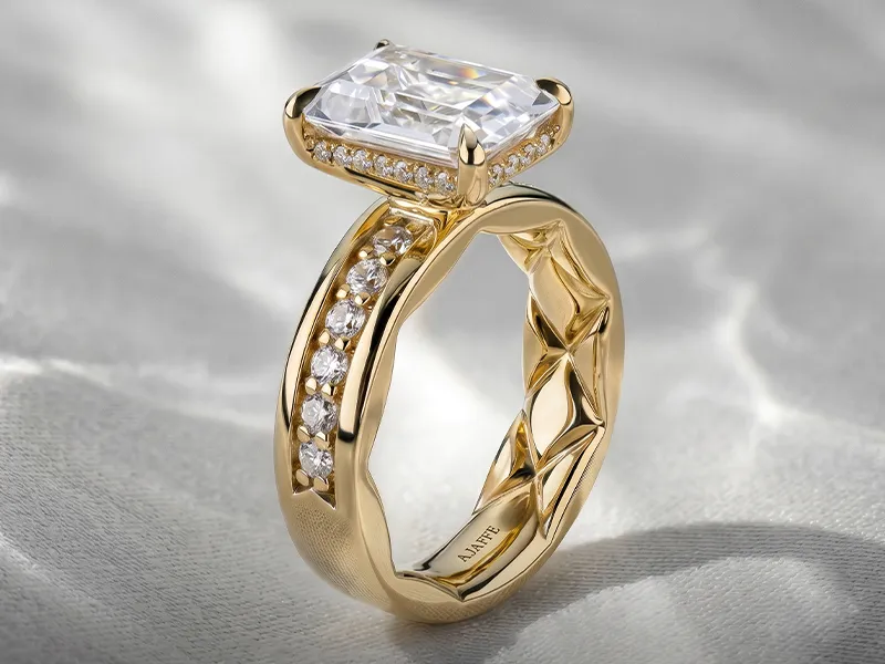 A gold engagement ring with a large rectangular diamond and smaller diamonds on the band.