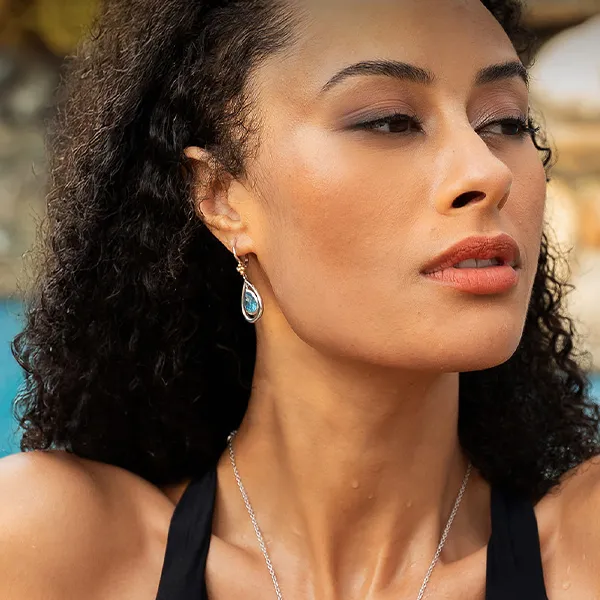 Model with curly hair wearing teardrop earrings, looking sideways.