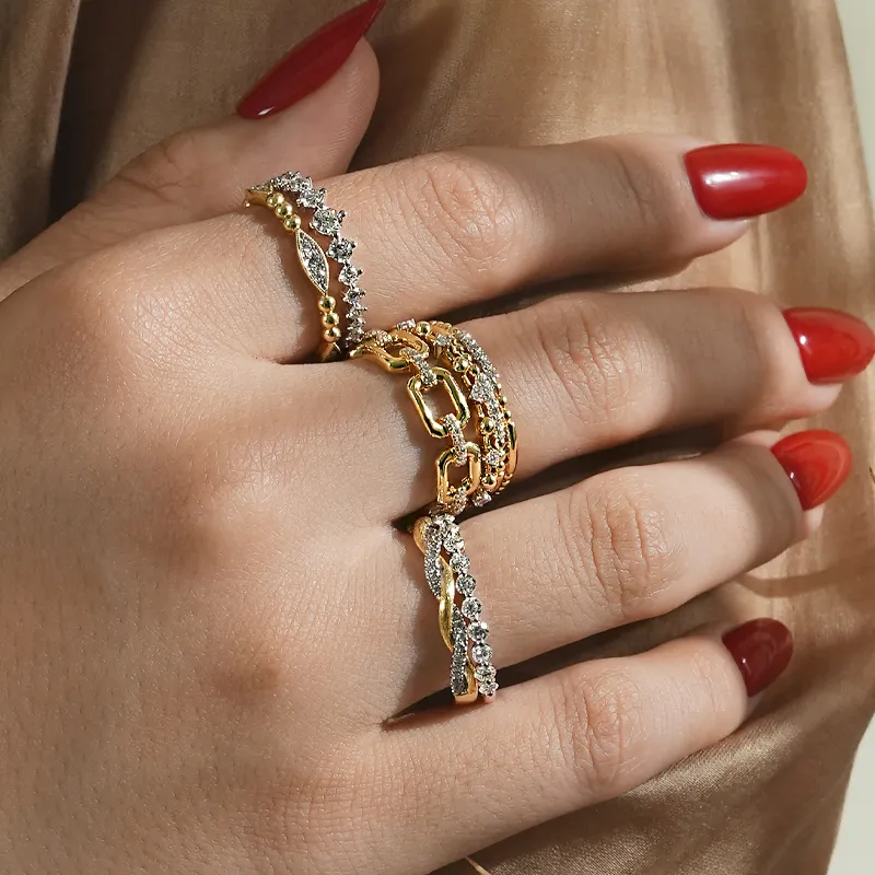 Elegant gold rings with gemstones on a hand with red nails.
