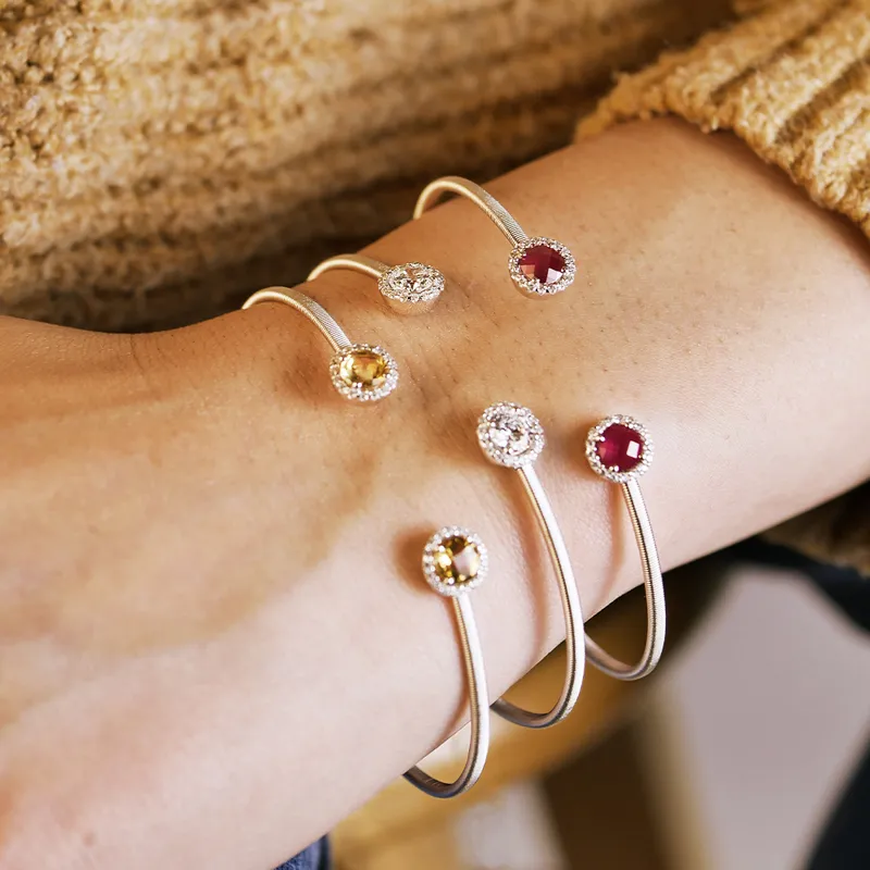 Three elegant bracelets with colorful gemstones on a wrist, showcasing fine jewelry.