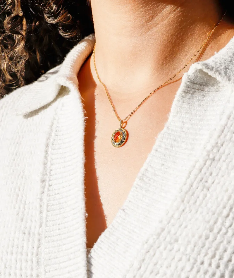 Model wearing a gold necklace with a colorful pendant.