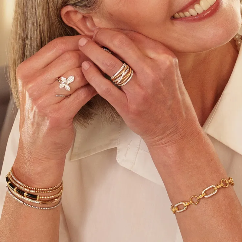 Close-up of a woman wearing gold and diamond jewelry, including rings and bracelets.