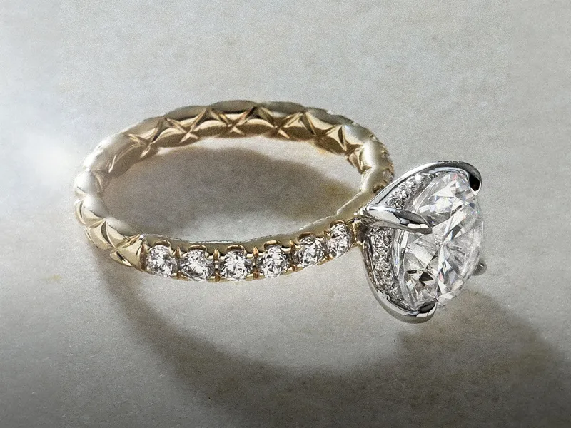 Elegant gold engagement ring with large diamond and smaller stones. Explore custom designs.