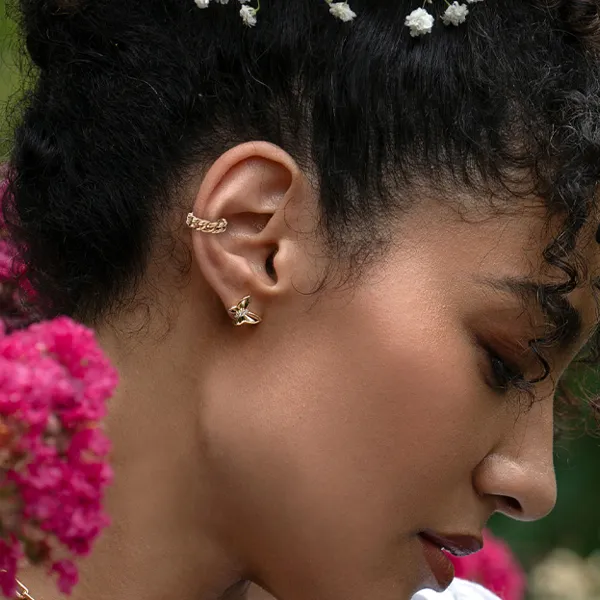 Model wearing gold earrings and ear cuff with flowers in hair. Explore more earrings at R. Gregory Jewelers.