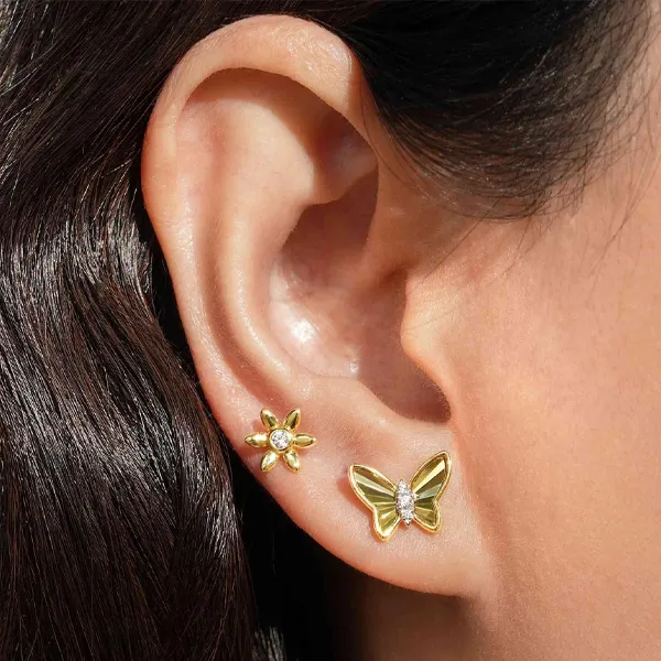 Gold butterfly and flower earrings displayed on a model's ear. Click to explore more earrings at R. Gregory Jewelers.