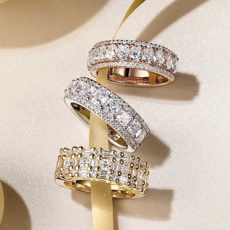 Three elegant diamond rings in gold and silver settings, displayed with a ribbon backdrop.