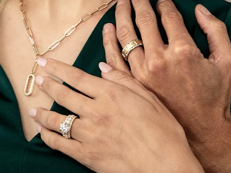 Elegant jewelry display featuring a woman's necklace and rings alongside a man's wedding band.