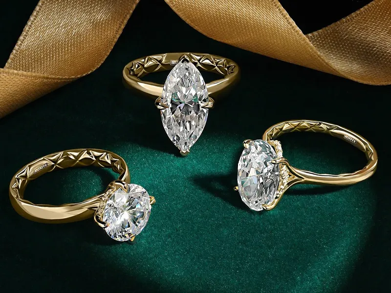 Three elegant gold engagement rings with large diamonds on a green velvet background.