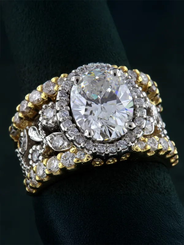 Stunning gold and silver ring featuring an oval diamond centerpiece surrounded by smaller diamonds. Visit Rich Custom Jewelry.