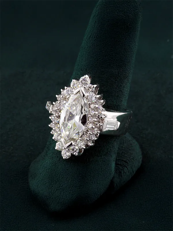 Gold diamond ring with intricate design featuring multiple sparkling stones, displayed on a green velvet stand.