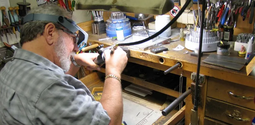 Jeweler working on a piece at a workshop filled with tools and equipment at Rich Custom Jewelry in Las Vegas.