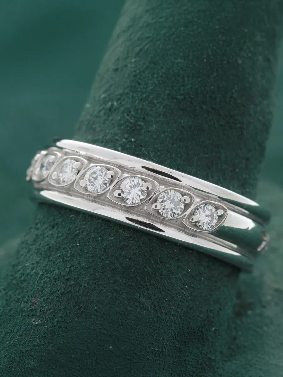 Elegant white gold band ring with five sparkling diamonds, displayed on a green velvet background.