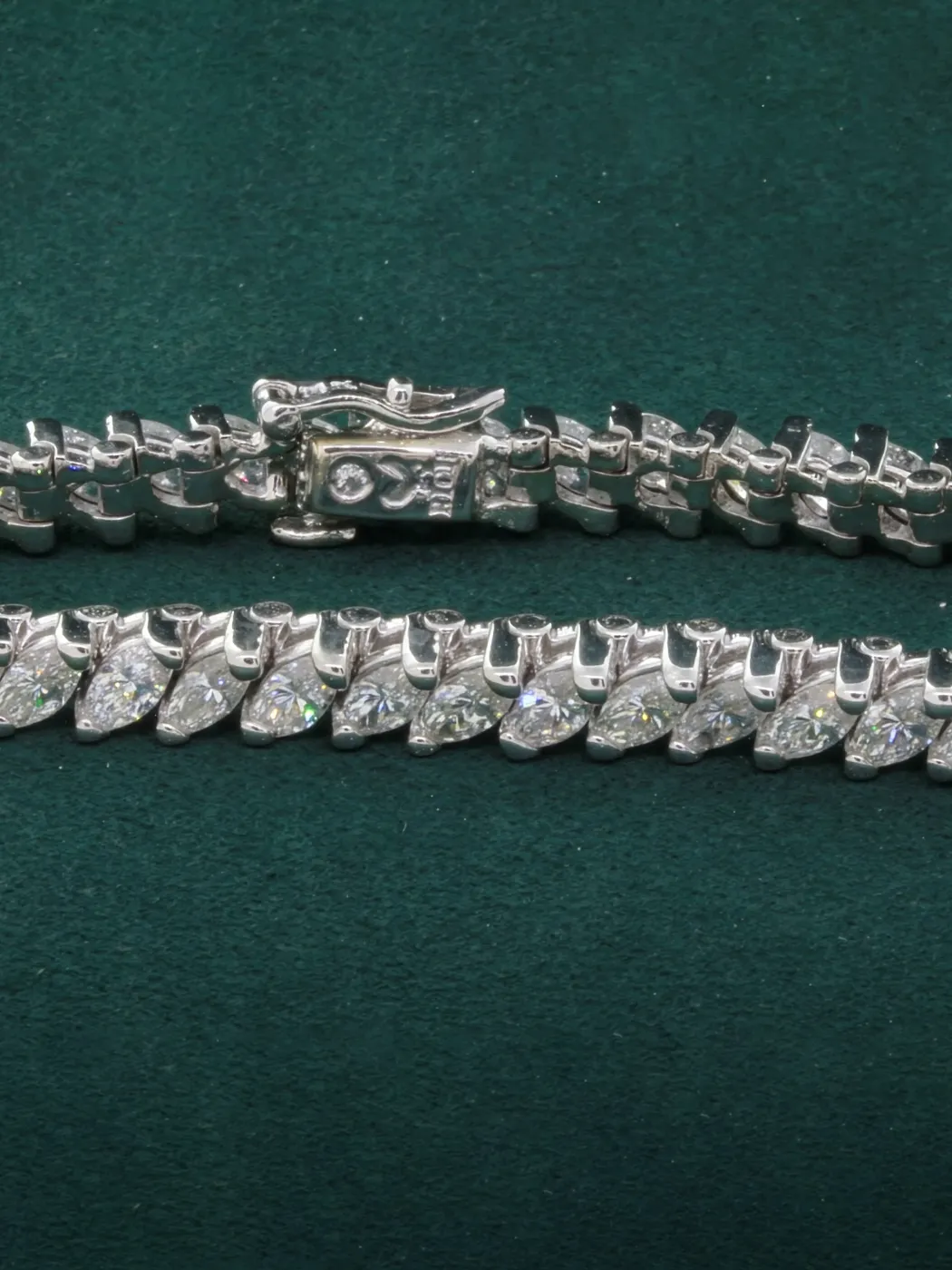 Two elegant diamond bracelets displayed on a green background, showcasing intricate designs and sparkling stones.